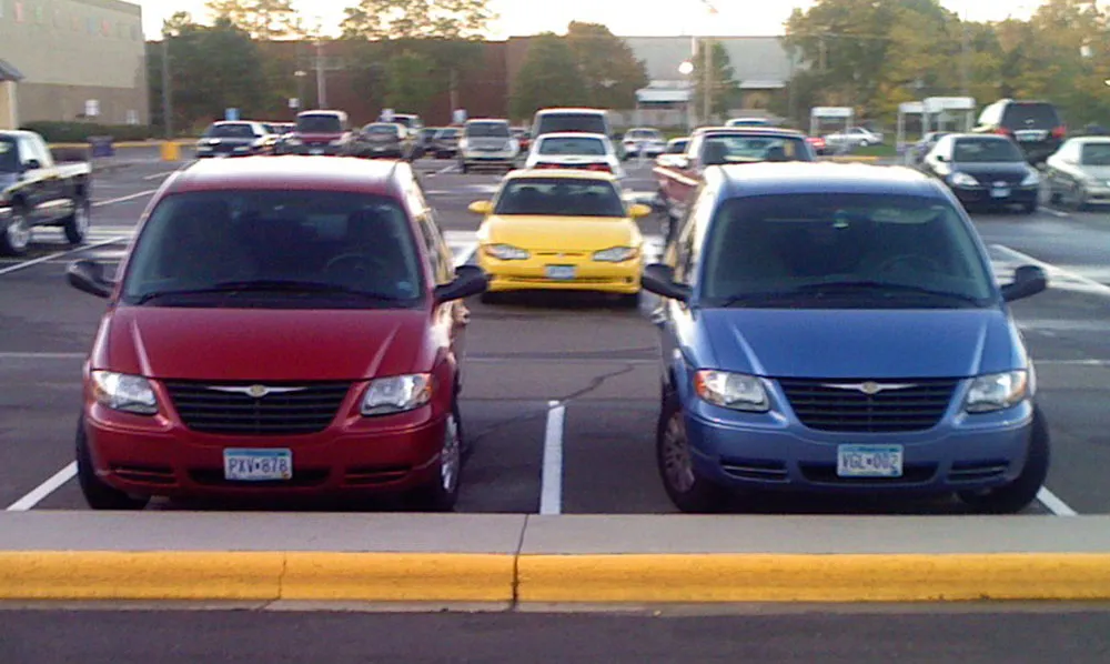 Blue, black and gray VW bugs in adjacent parking lot spaces.